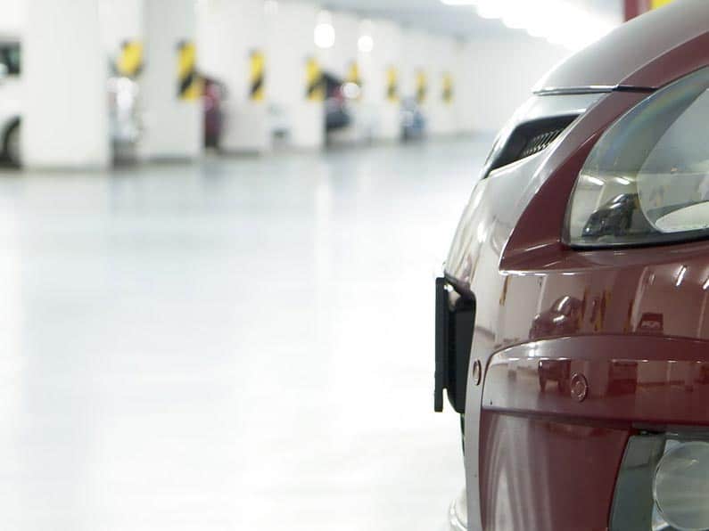 About Us: Parking Management - A dark red car parked in an underground parking